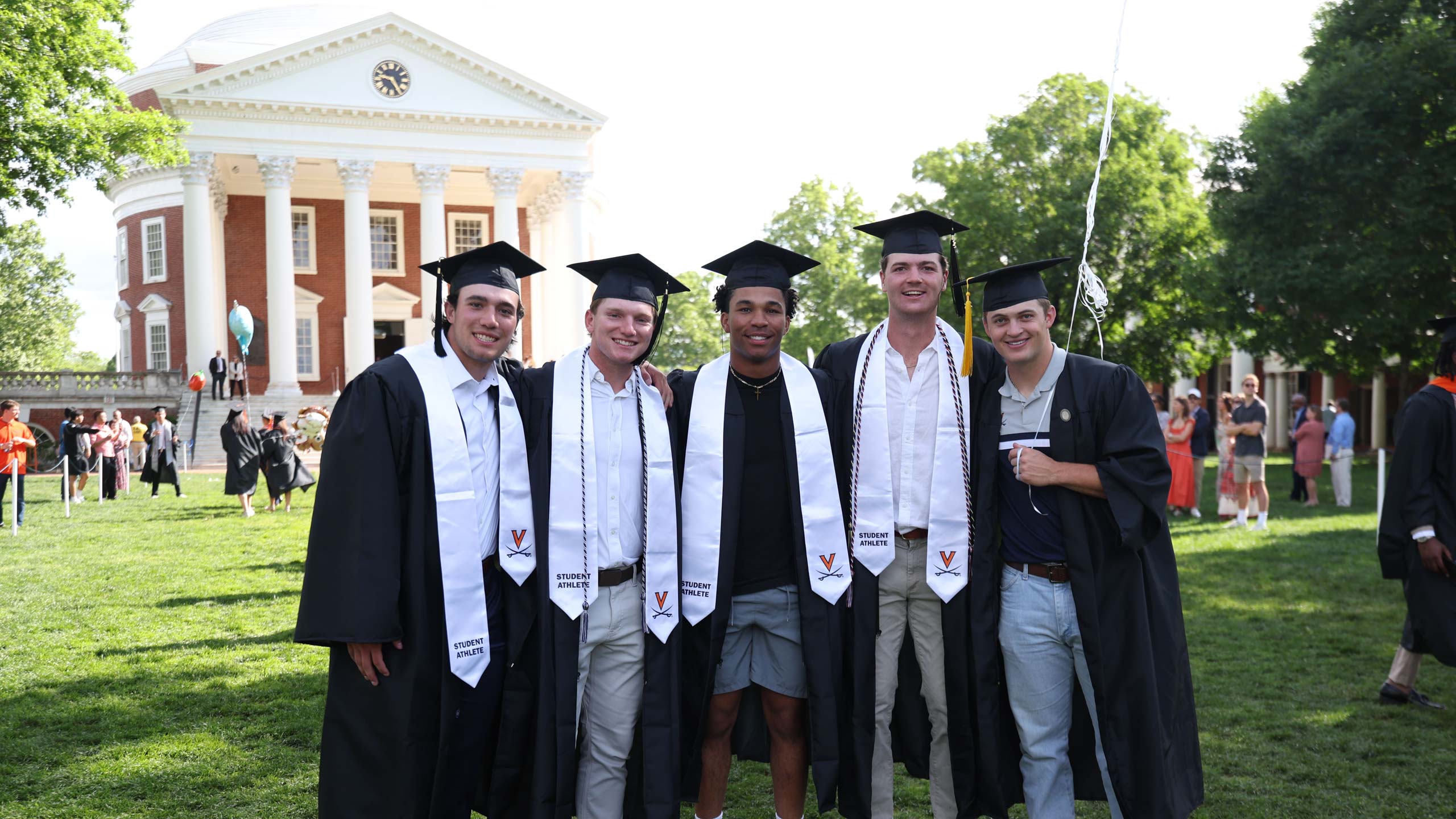 Five men posing together for photo in graduation cap and gowns