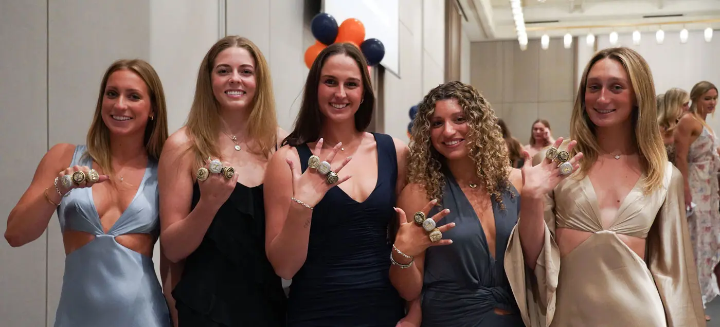 Women athletes posing with rings at a gala