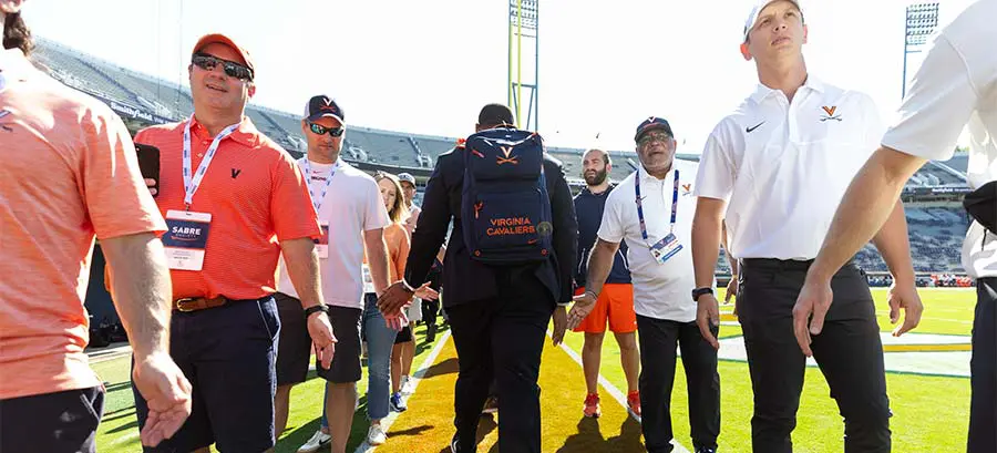 Two men shaking hands with other people around them on the field
