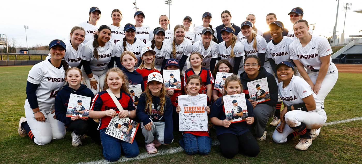 Softball team posing with kids on field